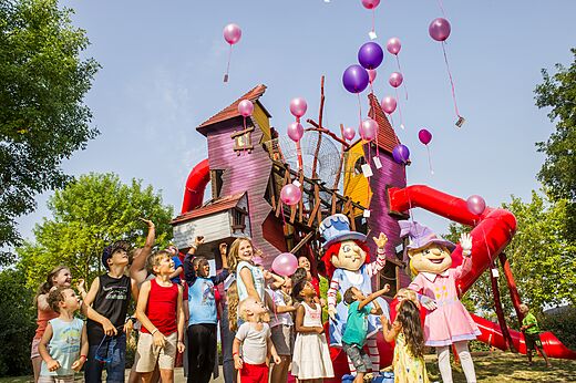Niños y mascotas frente a un área de juegos colorida con toboganes en el camping CAPFUN Curty's en Jard sur Mer (85).