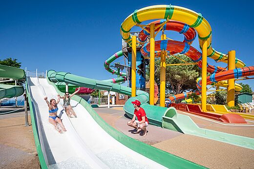 Toboganes acuáticos coloridos y niños divirtiéndose en el camping CAPFUN Curty's en Jard sur Mer (85).