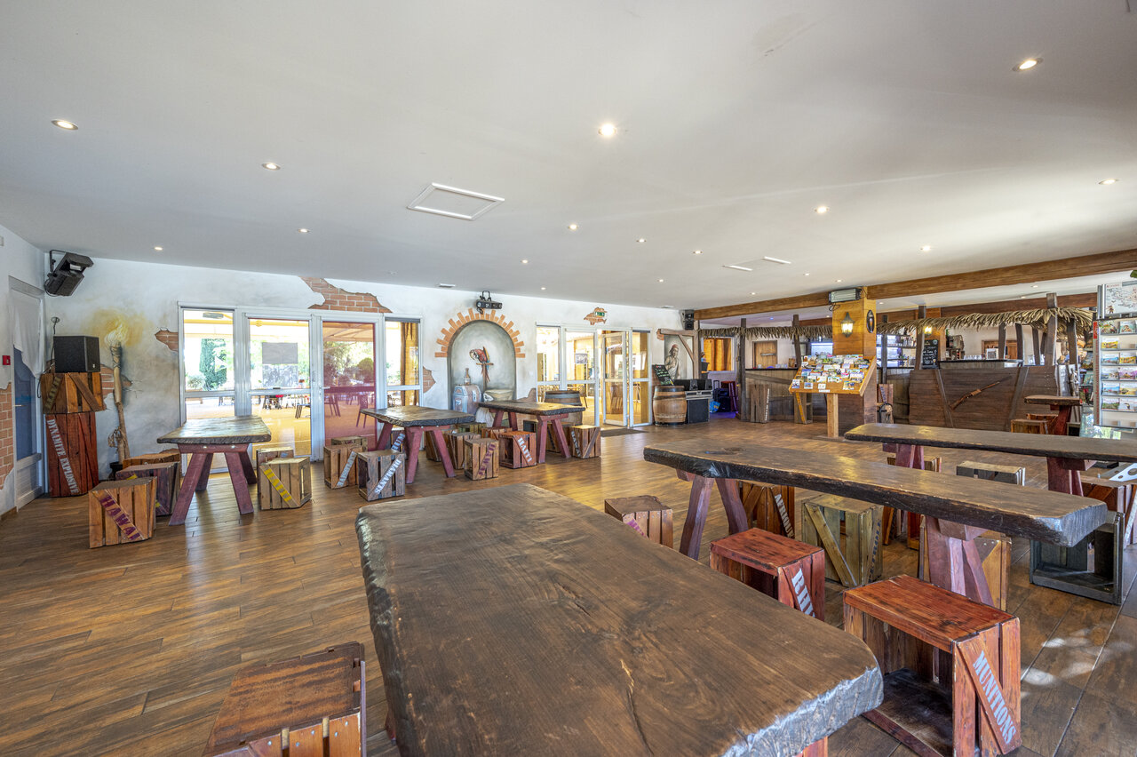 Bar y restaurante tem�tico con grandes mesas de madera en el camping CAPFUN Dauphins Bleus en GIVRAND (85).