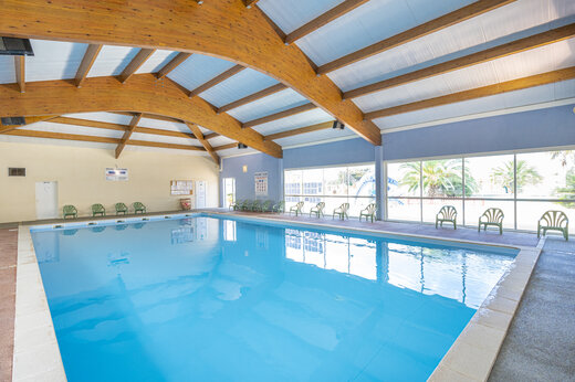 Piscina interior cubierta, estructura madera, grandes ventanas en camping CAPFUN Dauphins Bleus GIVRAND.