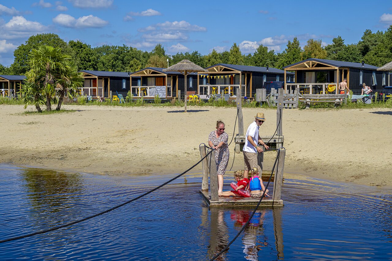 Familia en balsa, playa de arena y alojamientos en el camping CAPFUN De Belten en Rheeze.