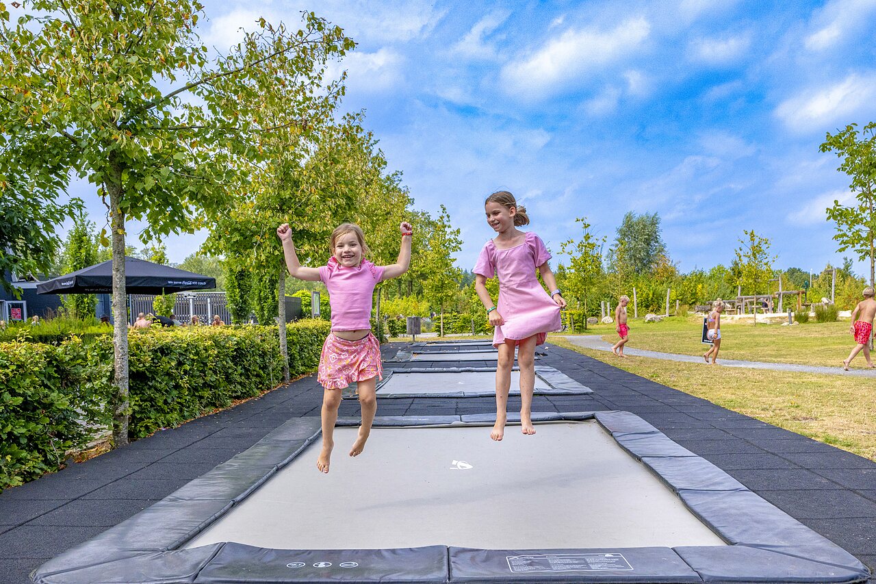 Ni�as felices saltando en trampolines integrados en el camping CAPFUN De Belten en Rheeze.