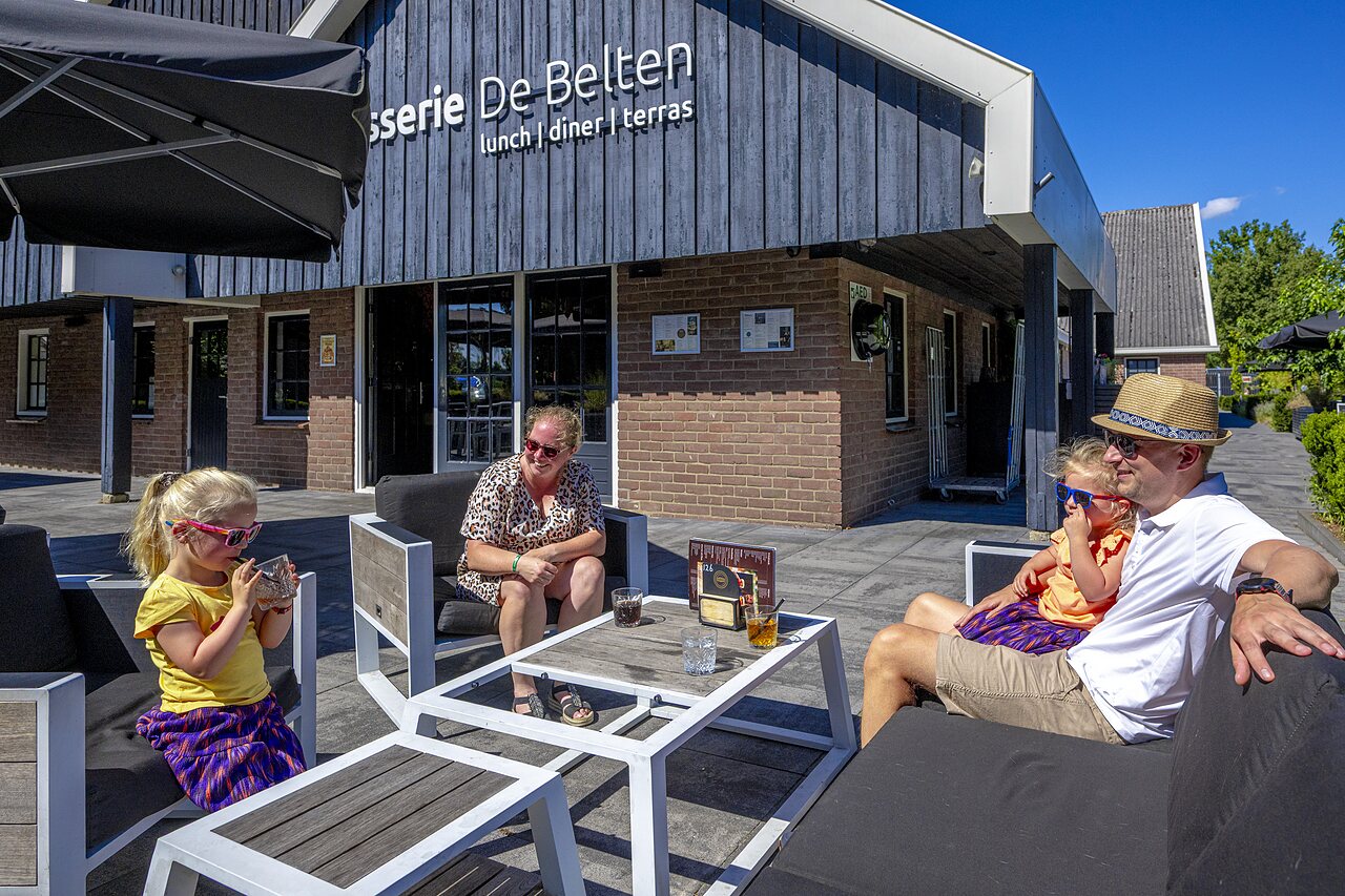 Familia disfrutando de la terraza de la brasserie en el camping CAPFUN De Belten en Rheeze.