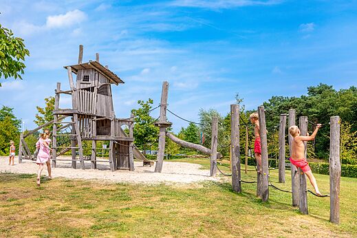 Gran parque infantil de madera con niños escalando en el camping CAPFUN De Belten en Rheeze.