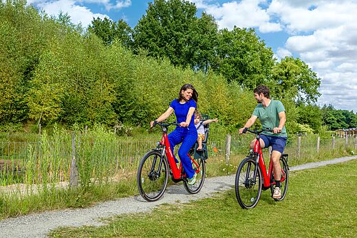 Familia en bicicleta con niño en camino verde al camping CAPFUN De Belten en Rheeze.