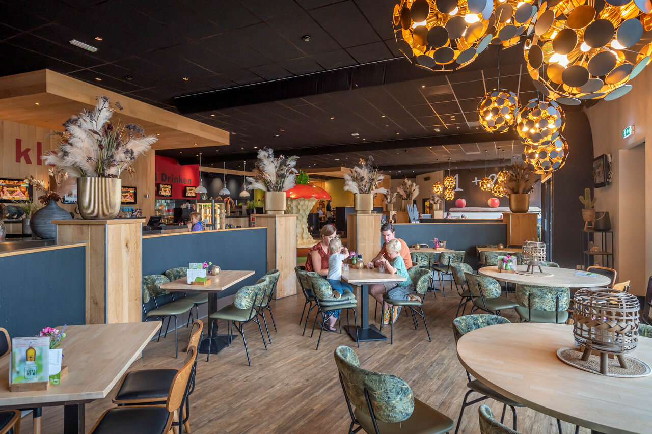 Restaurante moderno, familias, mesas y sillas en el camping CAPFUN De Bongerd en Tuitjenhorn.
