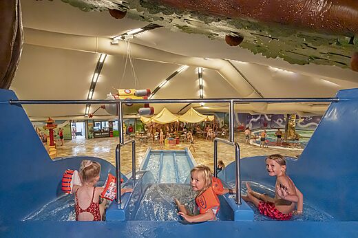 Niños en tobogán acuático interior y piscina en camping CAPFUN De Bongerd Tuitjenhorn.