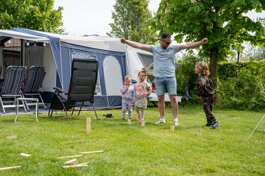 Familia jugando al juego de bolos suecos en una parcela del camping CAPFUN De Bongerd en Tuitjenhorn.