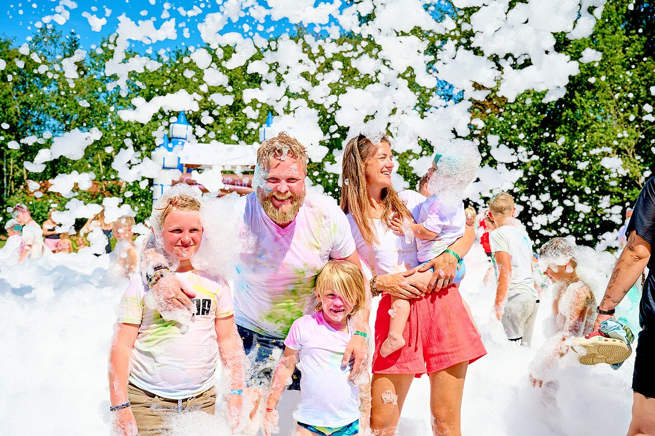 Familia feliz disfrutando de una fiesta de espuma en el camping CAPFUN De Eikenhof en Paasloo/Oldemarkt.