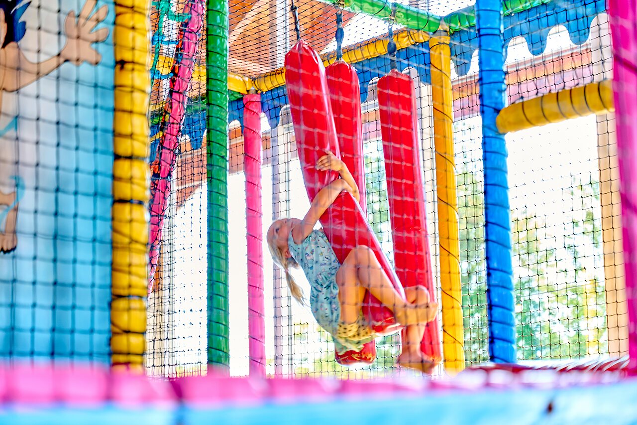 Ni�a jugando en colorida estructura de juegos interior en camping CAPFUN De Eikenhof.
