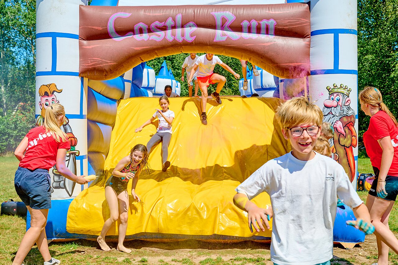 Ni�os disfrutando estructura hinchable Castle Run en camping CAPFUN De Eikenhof Paasloo/Oldemarkt.