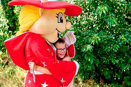 Niño sonriente abrazando la mascota del camping CAPFUN De Eikenhof en Paasloo/Oldemarkt.