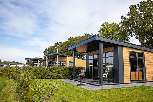 Mobil-homes modernos con terrazas y sillas en el camping CAPFUN De Eikenhof en Paasloo/Oldemarkt.