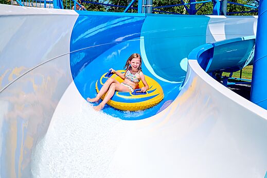 Niña sonriente en flotador en tobogán acuático en el camping CAPFUN De Eikenhof.