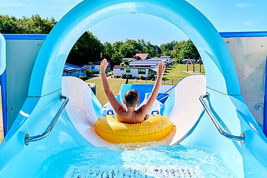 Tobogán acuático con niño en flotador en el camping CAPFUN De Eikenhof en Paasloo/Oldemarkt.
