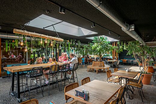Interior moderno del restaurante con mesas y familias en el camping CAPFUN De Pekelinge en Oostkapelle.