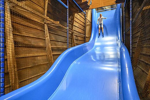 Tobogán gigante interior con niño deslizándose en el camping CAPFUN De Pekelinge en Oostkapelle.