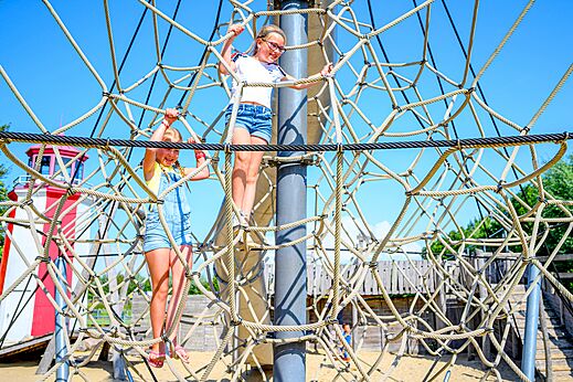 Niños escalando una estructura de juegos de red en el camping CAPFUN De Pekelinge en Oostkapelle.
