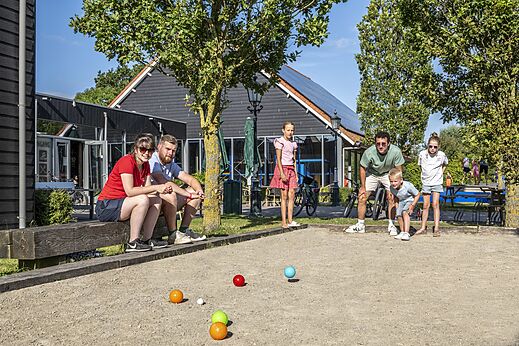 Familia jugando petanca en la cancha del camping CAPFUN De Pekelinge en Oostkapelle.