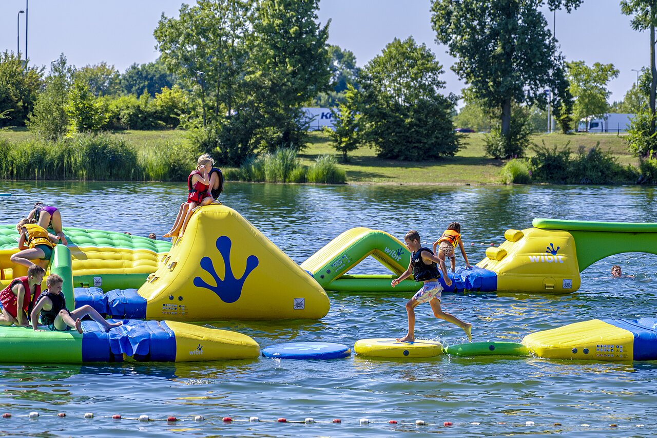 Parque acu�tico inflable Wibit en lago con ni�os en CAPFUN De Rotonde en Enspijk.