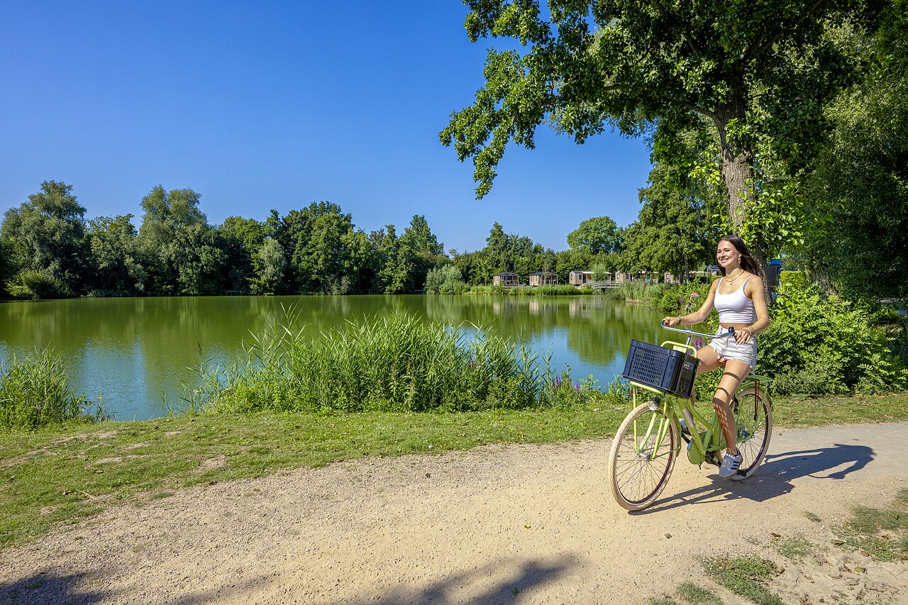 Joven en bicicleta, lago, naturaleza, alojamientos en el camping CAPFUN De Rotonde a Enspijk.