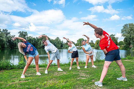 Jóvenes haciendo estiramientos con animador en el camping CAPFUN De Rotonde a Enspijk.