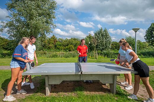 Jóvenes jugando al tenis de mesa exterior en el camping CAPFUN De Rotonde en Enspijk.