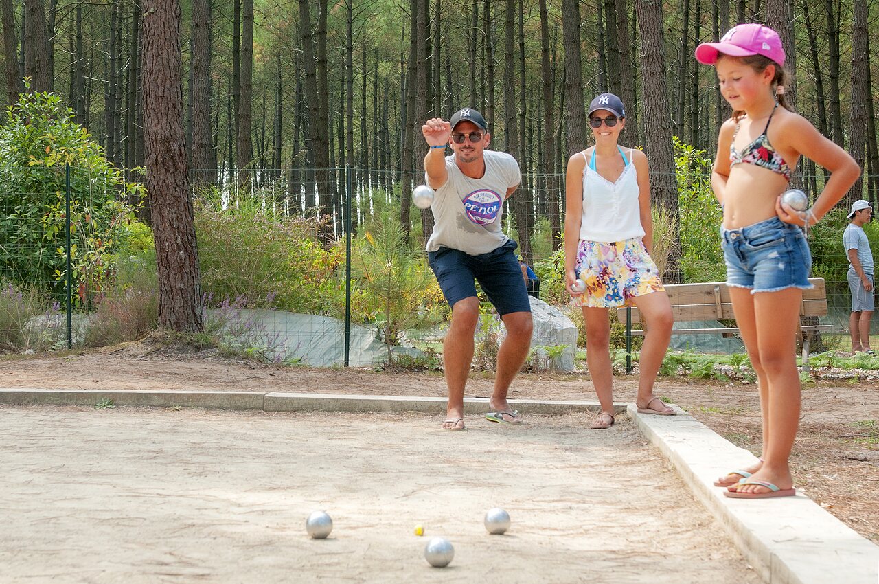 Familia jugando a la petanca en una cancha sombreada en el camping CAPFUN De Scheepsbel en Doornspijk.
