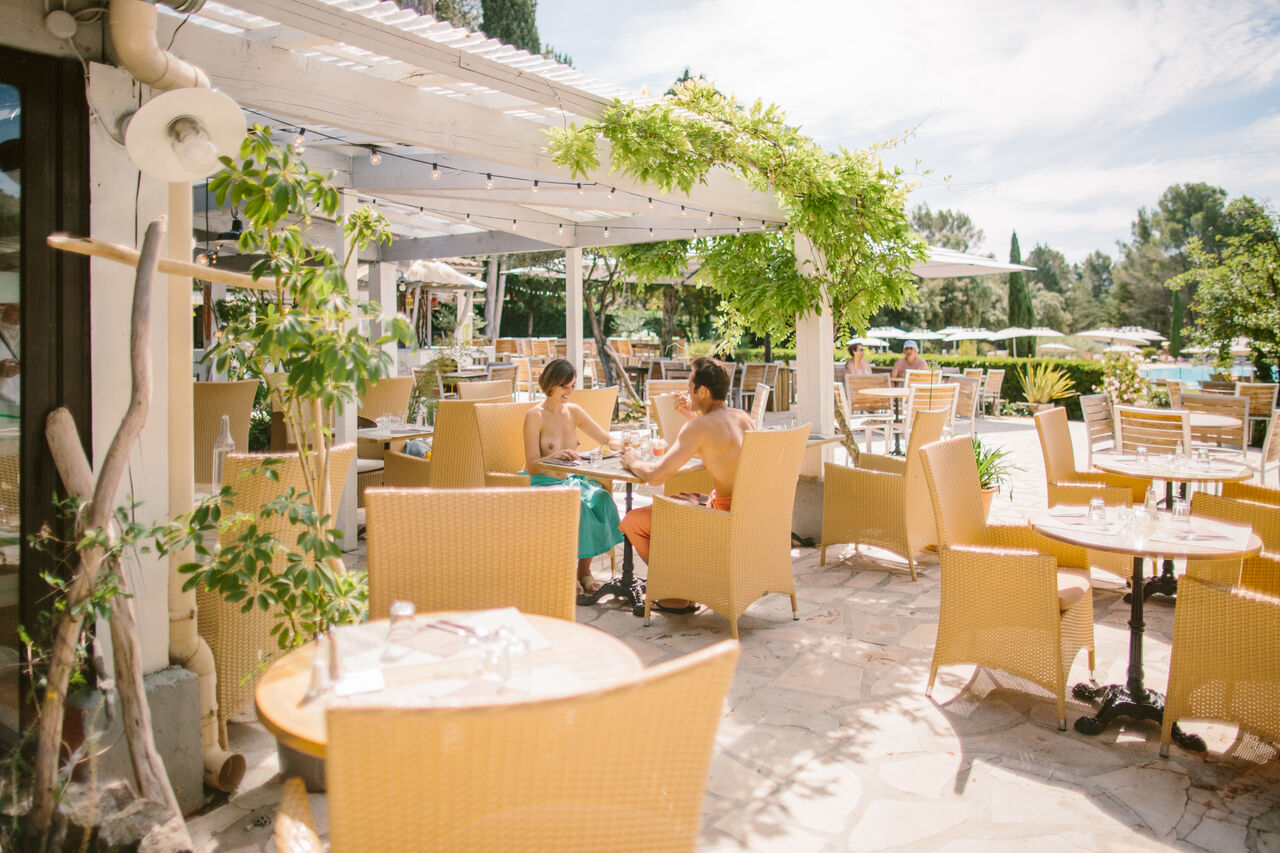 Pareja naturista almorzando en terraza sombreada del restaurante en camping LIBRANOO Naturiste Belezy en B�doin (84).