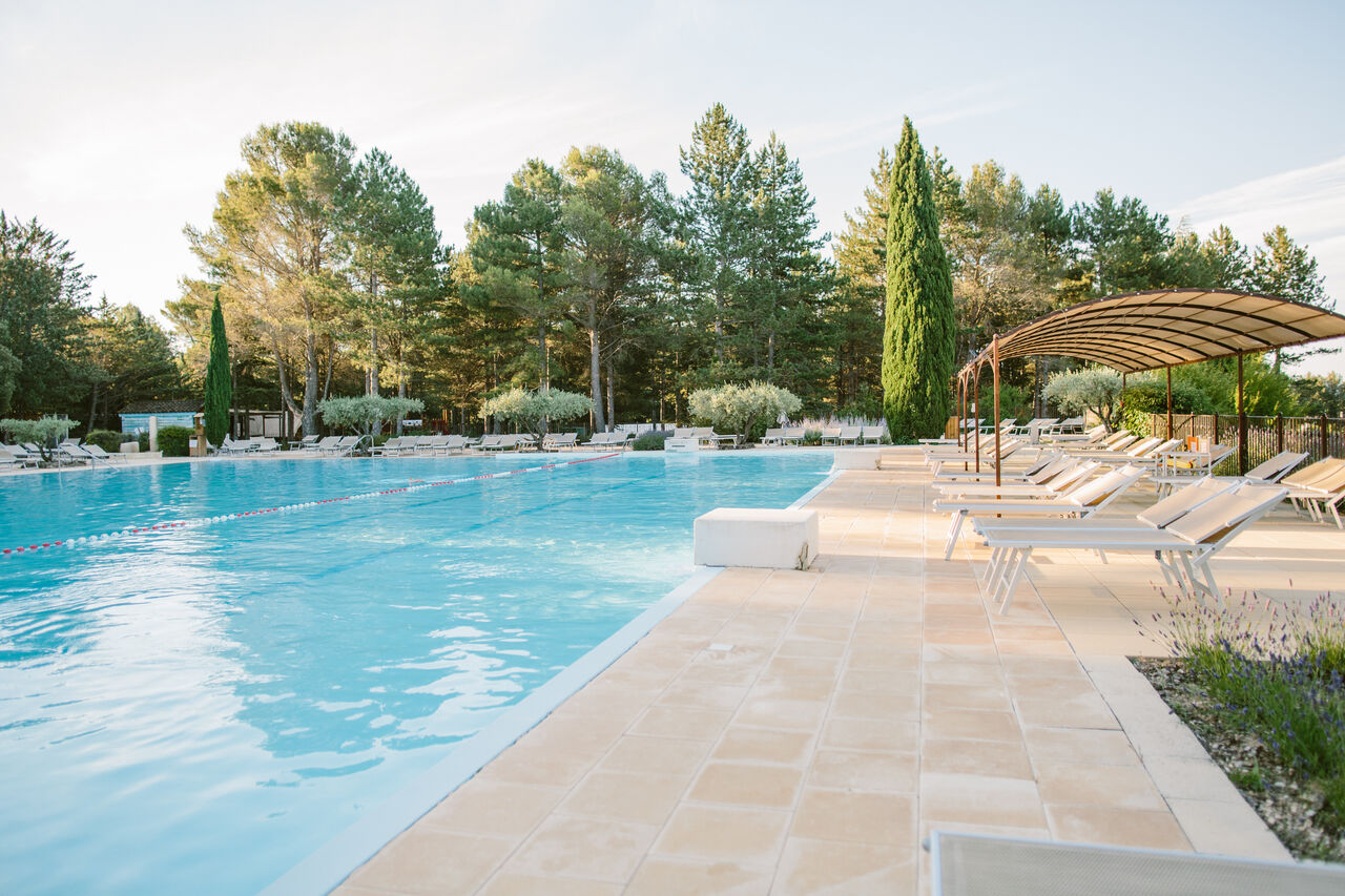 Gran piscina exterior con tumbonas y zona de sombra en el camping LIBRANOO Naturiste Belezy en B�doin (84).