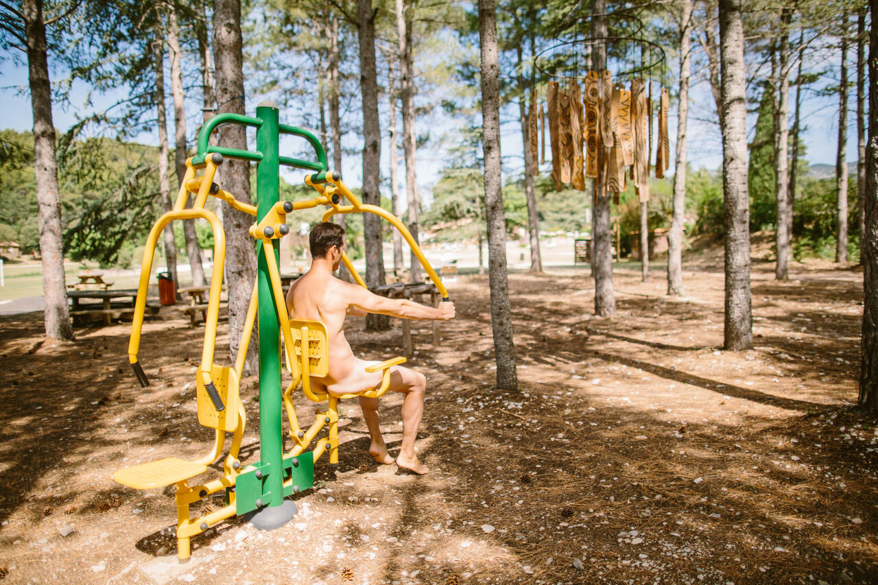 Hombre naturista usando m�quina de ejercicio al aire libre en camping LIBRANOO Naturiste Belezy en B�doin (84).