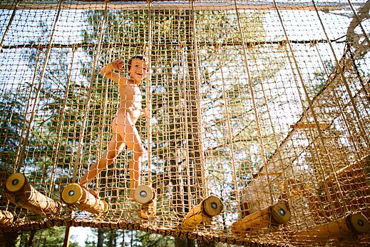 Niño naturista jugando en estructura de red en camping LIBRANOO Naturiste Belezy.