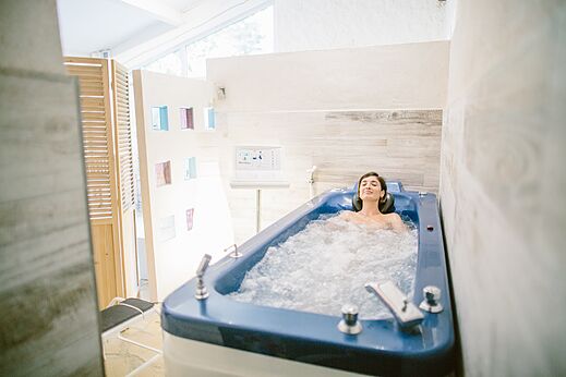 Mujer relajándose en una bañera de hidroterapia en el camping LIBRANOO Naturiste Belezy en Bédoin (84).