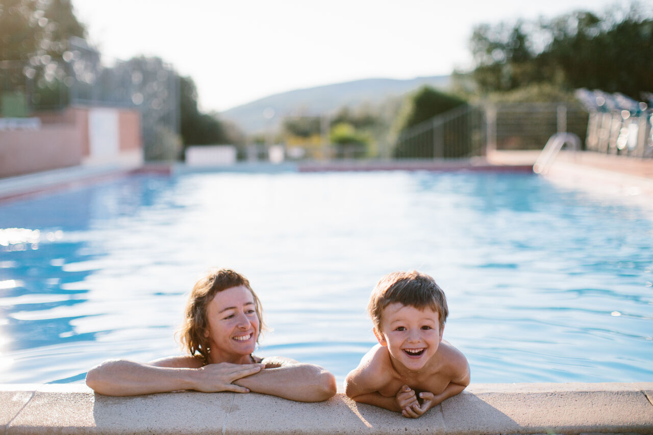 Familia sonriente en la piscina del camping LIBRANOO Naturiste Sabliere en Barjac (30).