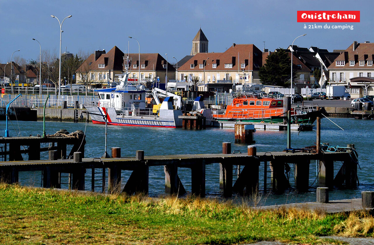 Puerto de Ouistreham con barcos, casas y campanario de iglesia en Normand�a.