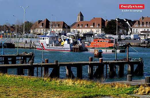 Puerto de Ouistreham con barcos amarrados y casas tradicionales en Normandía.