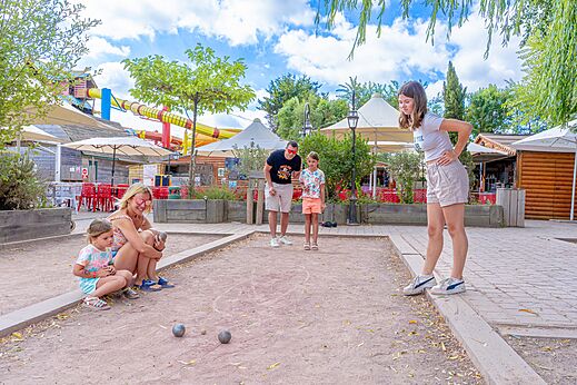Familia jugando a la petanca en una cancha dedicada en el camping CAPFUN Donjon de Lars en Courseulles-sur-Mer (14).