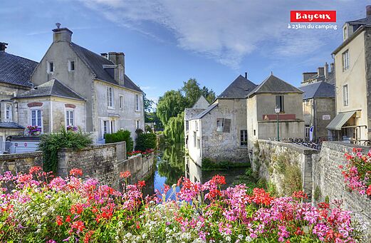 Canal florido y casas históricas en Bayeux, ciudad para visitar en Normandía.
