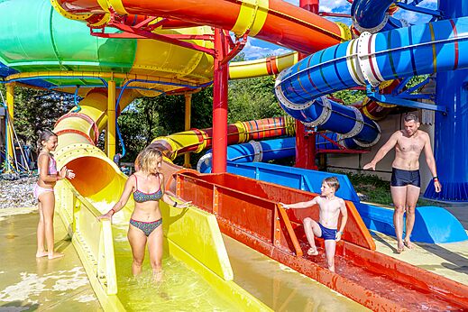 Familia disfrutando de toboganes acuáticos coloridos en camping CAPFUN Donjon de Lars en Courseulles-sur-Mer (14).