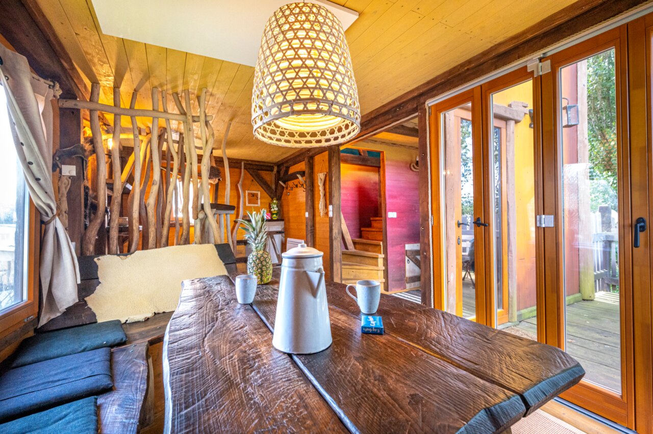 Interior r�stico Casa en el �rbol, mesa de madera, en el camping CAPFUN Donjon de Lars: Casas en los �rboles en Courseulles-sur-Mer (14).