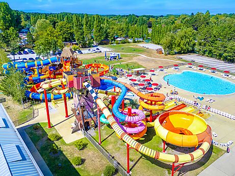 Toboganes acuáticos coloridos y gran piscina exterior vistos desde el cielo en el camping CAPFUN Dune Fleurie en Quend Plage (80).