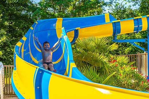 Ni�o sonriente bajando tobog�n acu�tico azul y amarillo en camping CAPFUN Duravel (46).