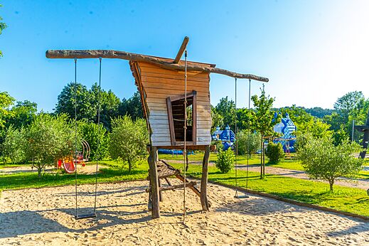 �rea de juegos con caba�a de madera y columpios en el camping CAPFUN Duravel.