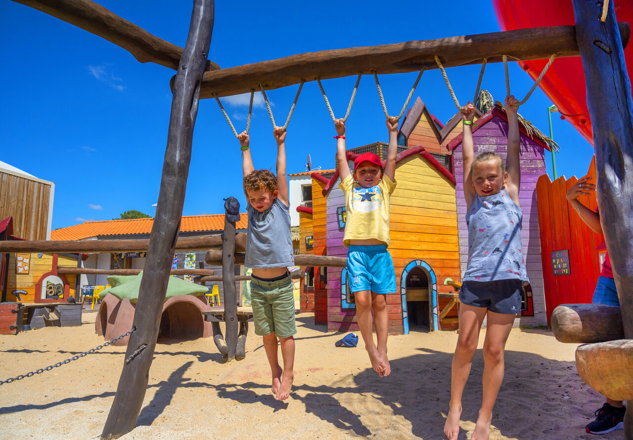Tres ni�os sonrientes juegan en barras de mono en el camping CAPFUN Ecureuils en JARD SUR MER (85).