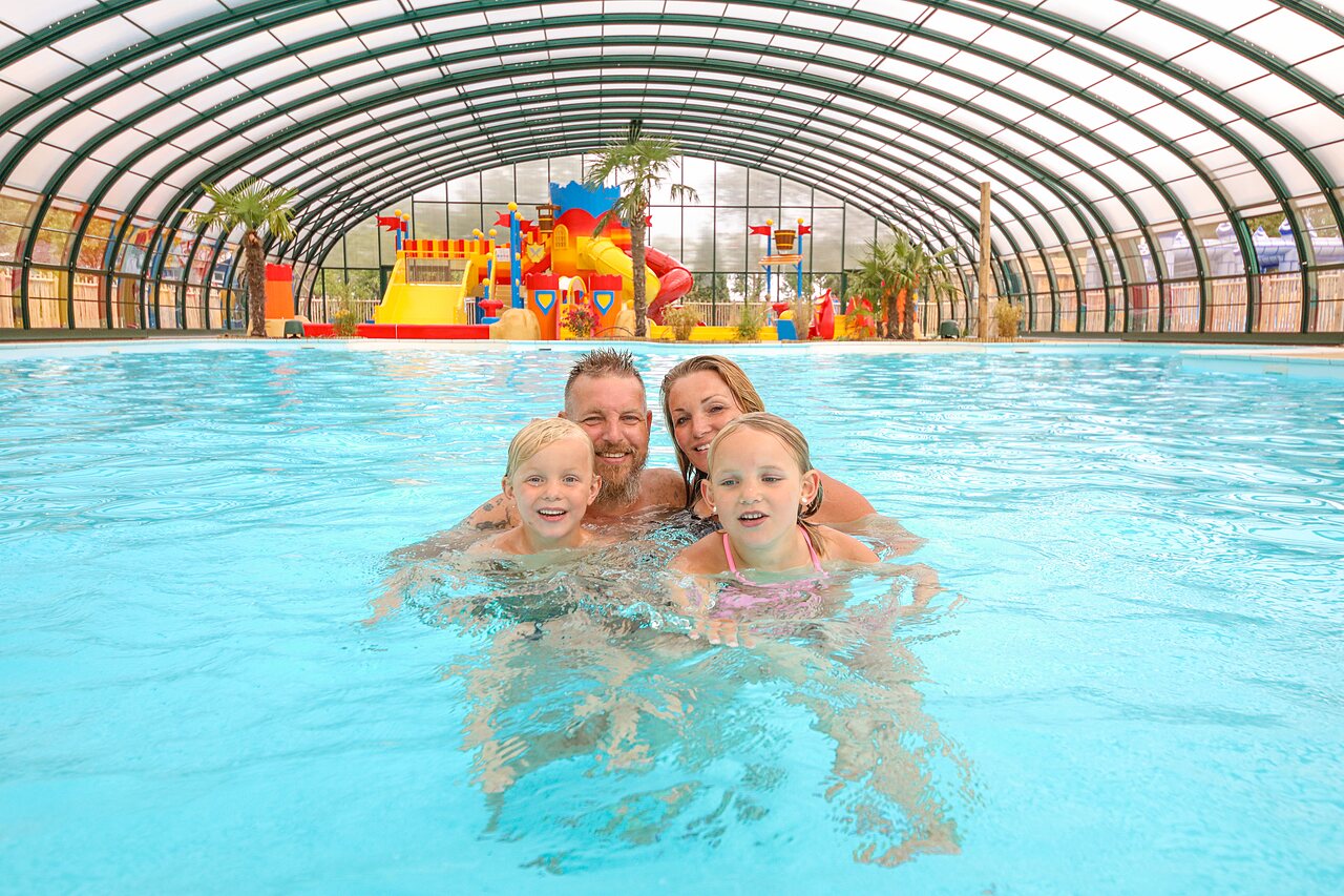 Familia sonriente en piscina cubierta con juegos acu�ticos en CAPFUN Eibernest.
