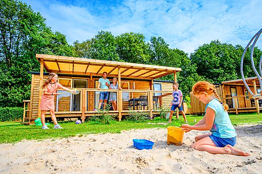Familia jugando frente a Mobil-home de madera en camping CAPFUN Eibernest, Eibergen.
