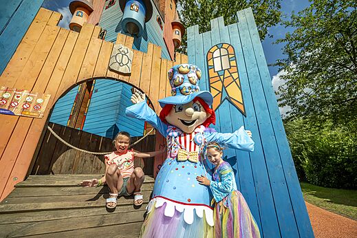 Niños y mascota frente a zona de juegos colorida en camping CAPFUN Eibernest en Eibergen.