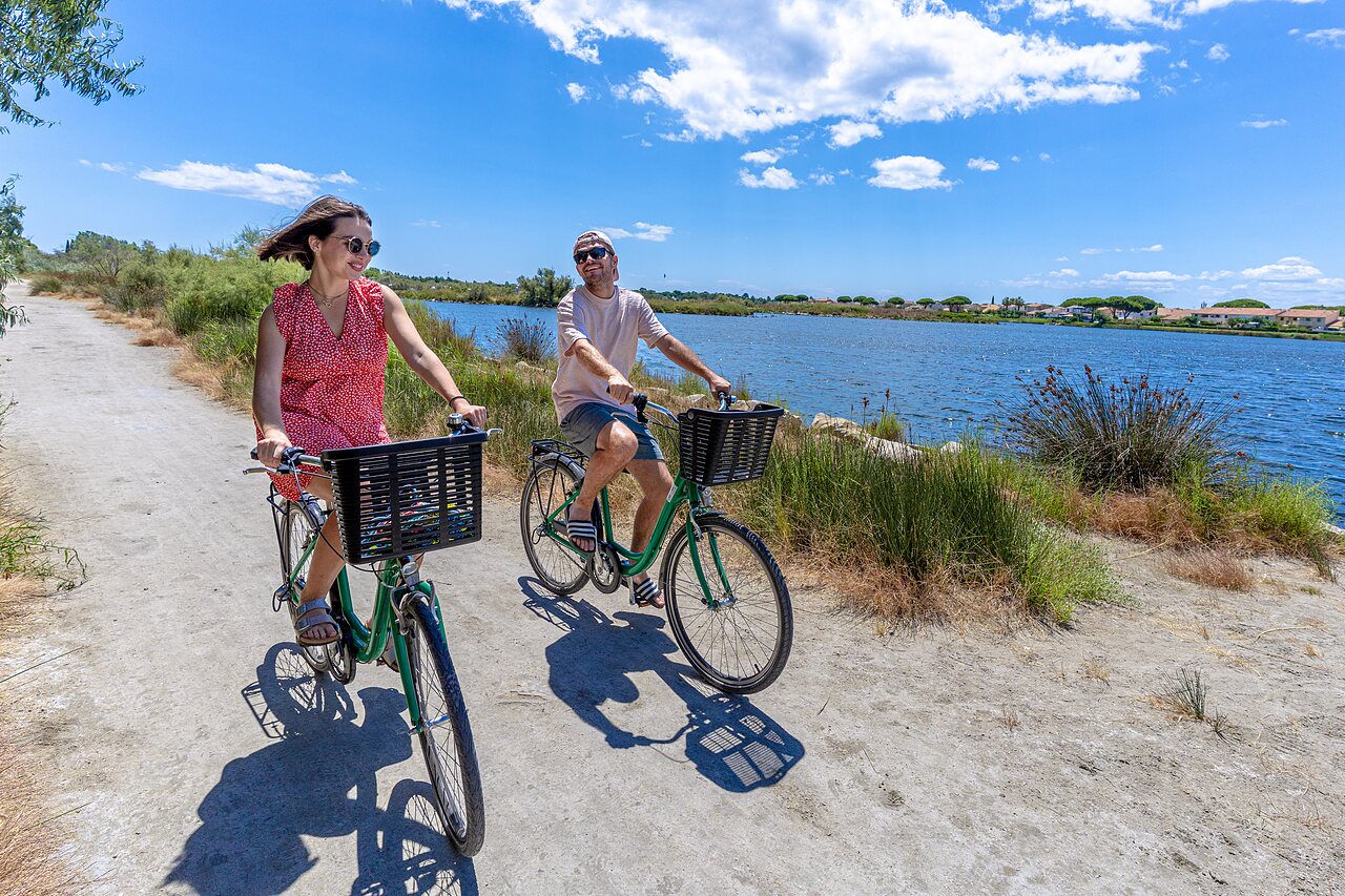 Pareja en bicicleta junto al lago en el camping VAGUES OCEANES Elys�e en Le Grau du Roi.