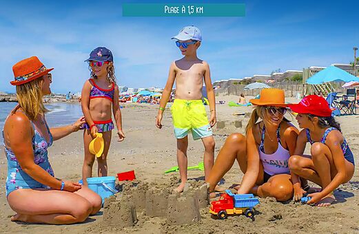 Familia con niños jugando en la playa de arena en el camping VAGUES OCEANES Elysée en Le Grau du Roi (30).