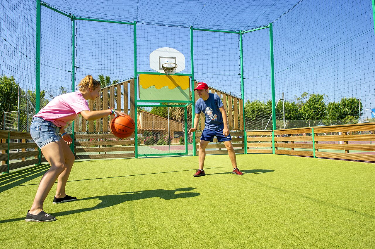J�venes jugando baloncesto en cancha multideporte en el camping CAPFUN El Moli en Elne (66).